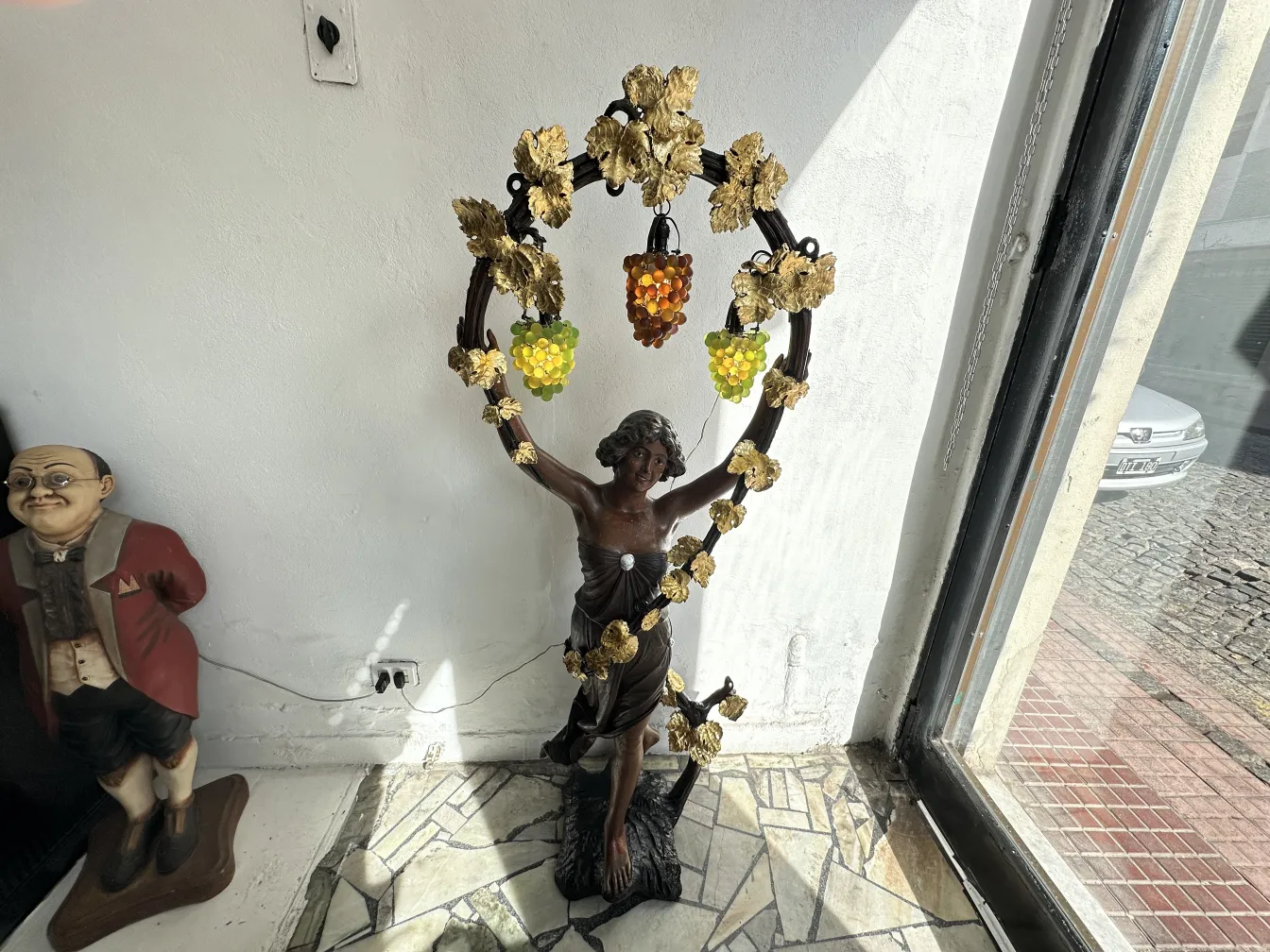 Antique sculpture of a figure with grapes and decorative leaves.