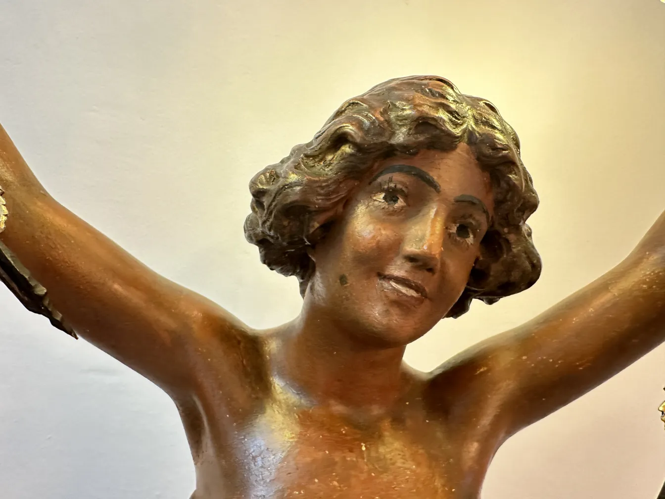 Antique sculpture depicting a smiling human figure, with detailed hair.