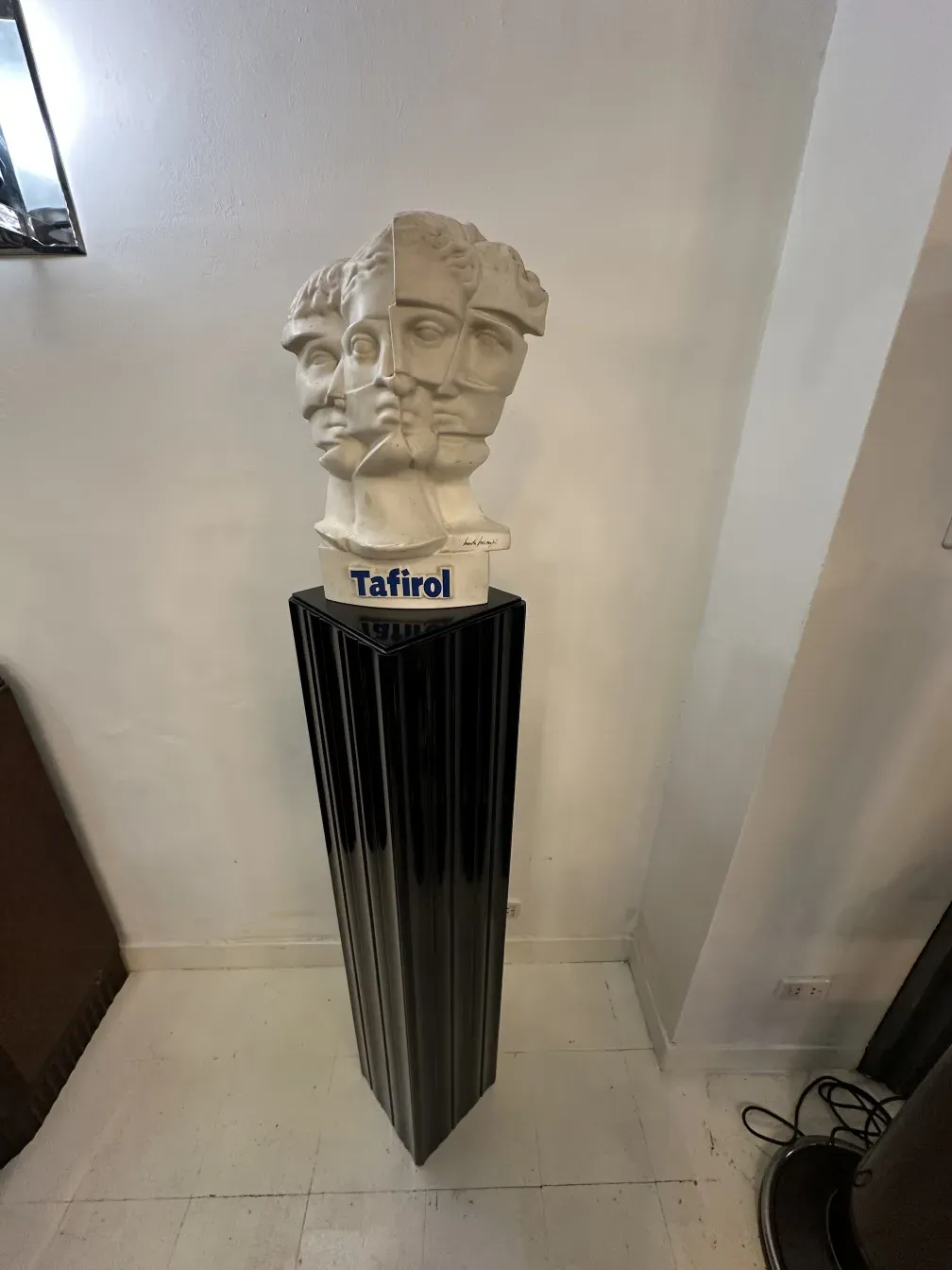 Antique column with sculpture on top and decorative base in a modern setting