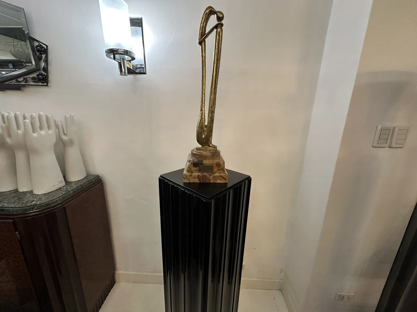 Antique decorative column with a statue on top, surrounded by an elegant setting.