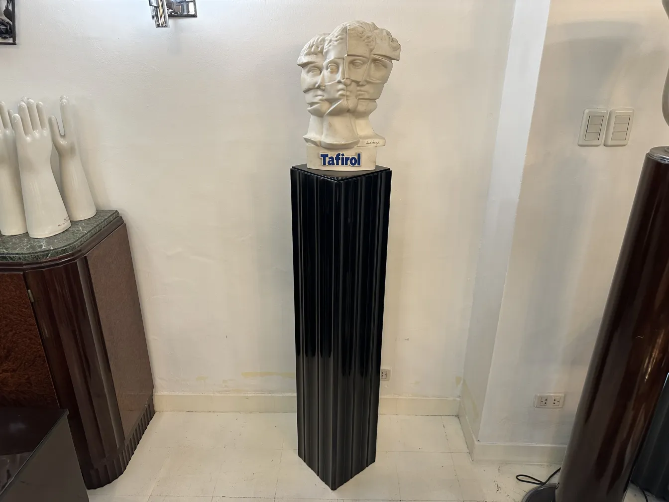 Antique black column with a sculpture on top. Modern setting.