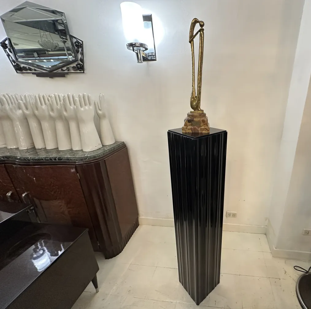 عمود زخرفي قديم مع تمثال في الأعلى، محاط بأيدٍ بيضاء.