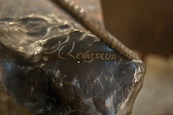 Scultura antica con firma visibile e dettaglio sottile.