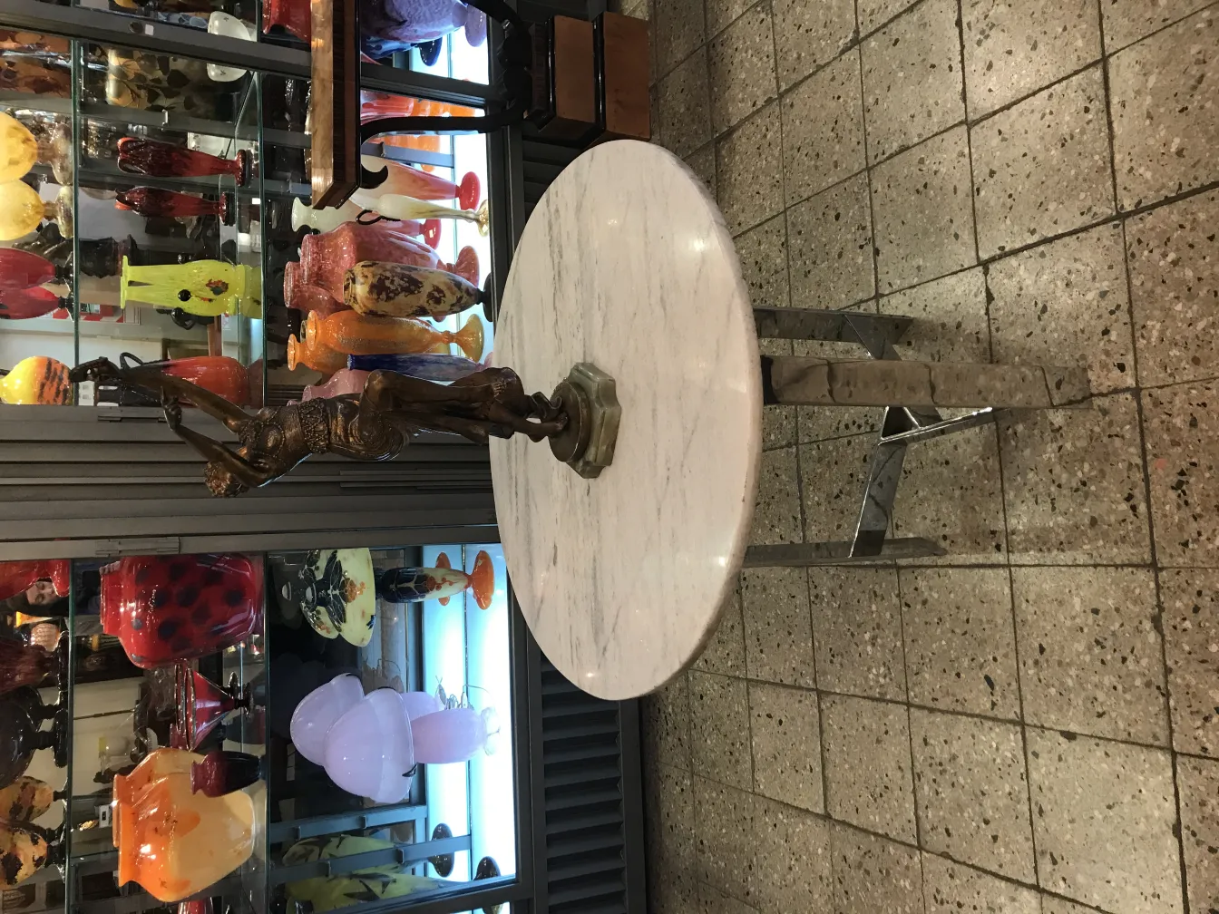 escultura antigua con base sobre mesa, decoraciones de vidrio de fondo