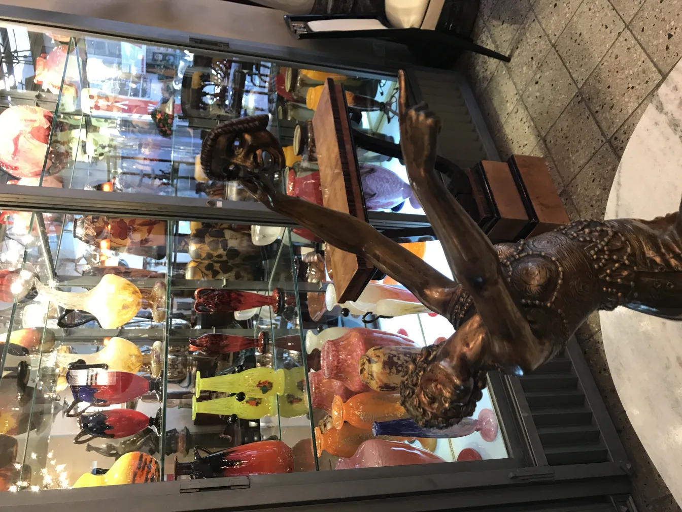 escultura antiga representando figura em movimento entre objetos decorativos