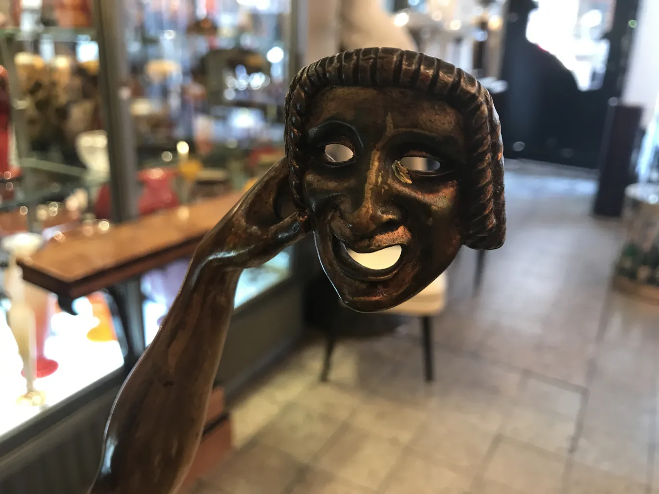 escultura antiga com detalhes de rosto e mão, ambiente de antiguidades