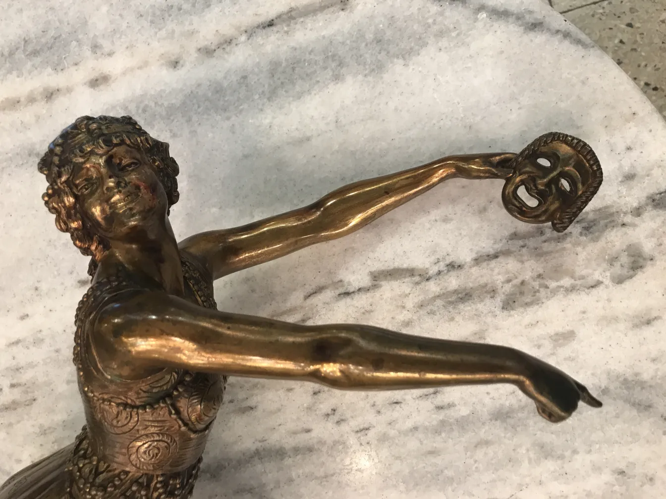 antique sculpture featuring human figure and theatrical mask