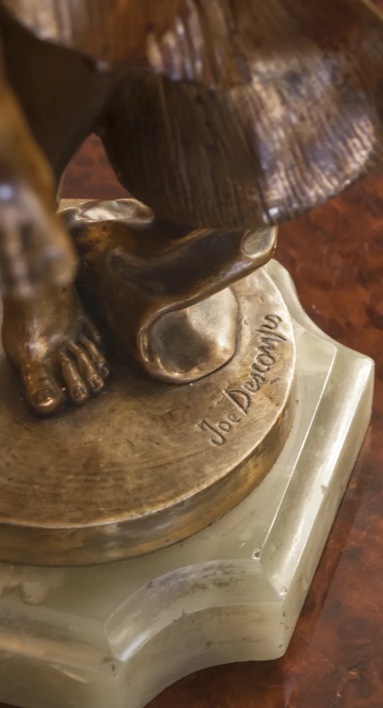 escultura antigua con pie visible y firma en la base