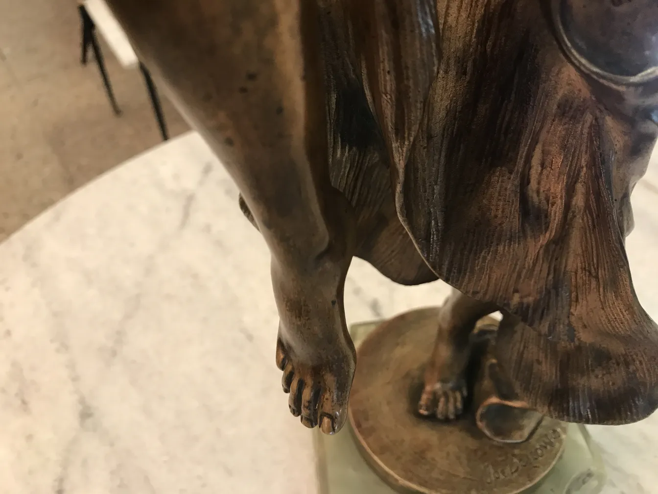 Antike Skulptur mit sichtbaren Details und dekorativem Sockel.