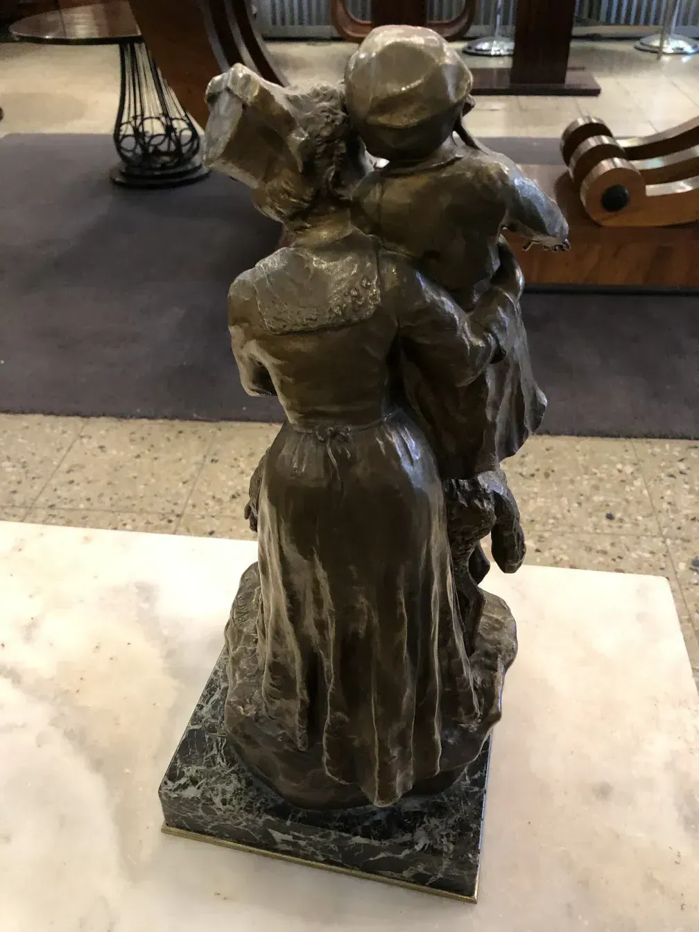 escultura antiga com uma figura humana segurando uma criança, fundo neutro