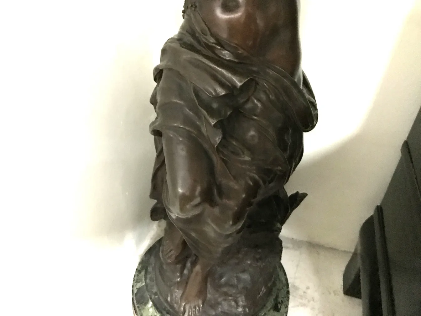 escultura antigua de un personaje en pie, con detalles en la vestimenta