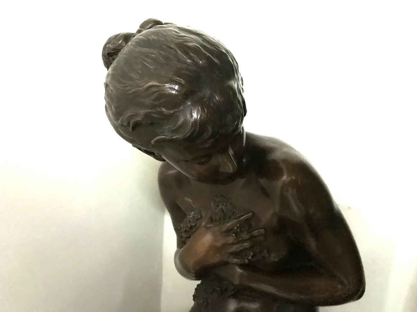 escultura antigua con figura femenina en pose contemplativa