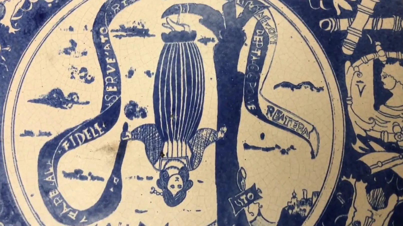 Prato de cerâmica antiga com detalhes azuis e figuras pintadas.