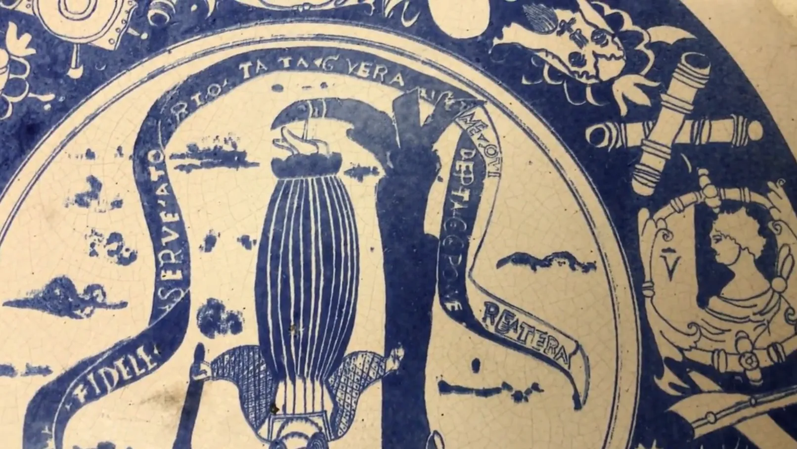 Placa de cerâmica antiga decorada em azul e branco com desenhos intrincados.