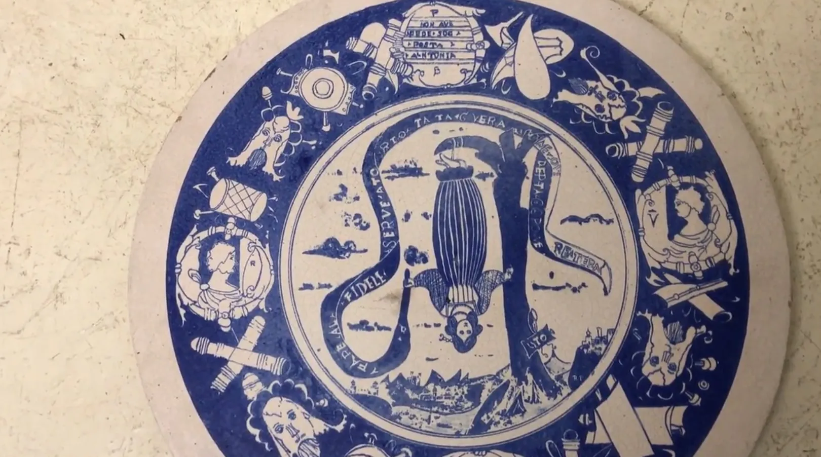 Ancient ceramic plate with blue aquatic designs on a light background.