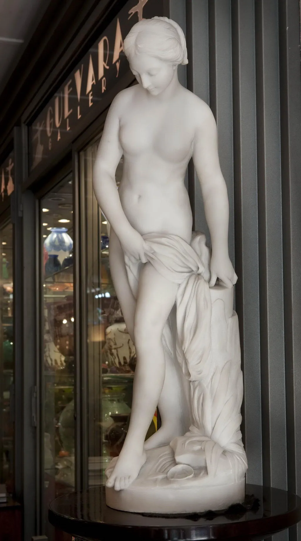 escultura antiga de mulher com tecido em ambiente de galeria