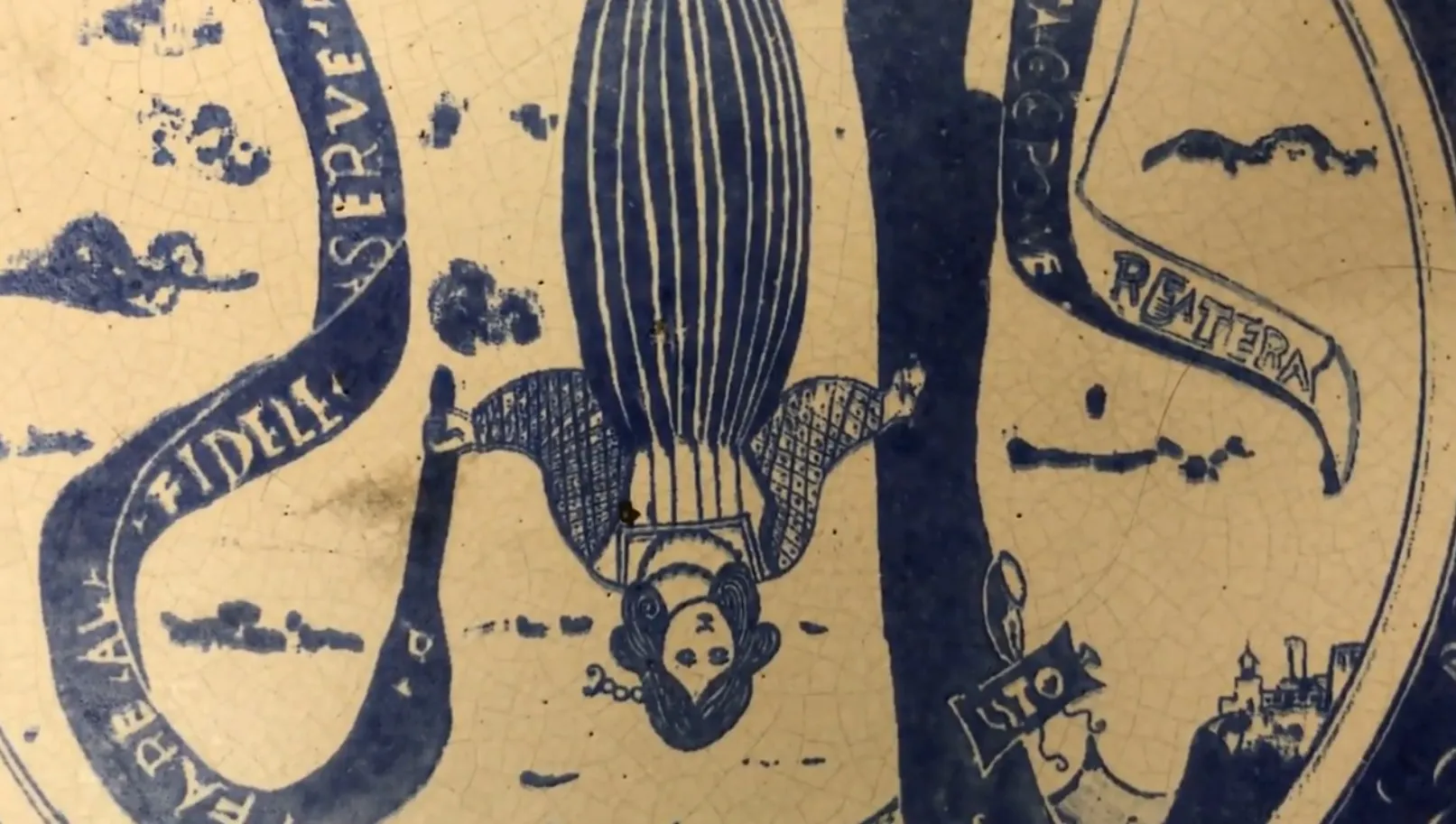 Cerámica antigua con dibujo de mujer en azul, decoraciones detalladas.