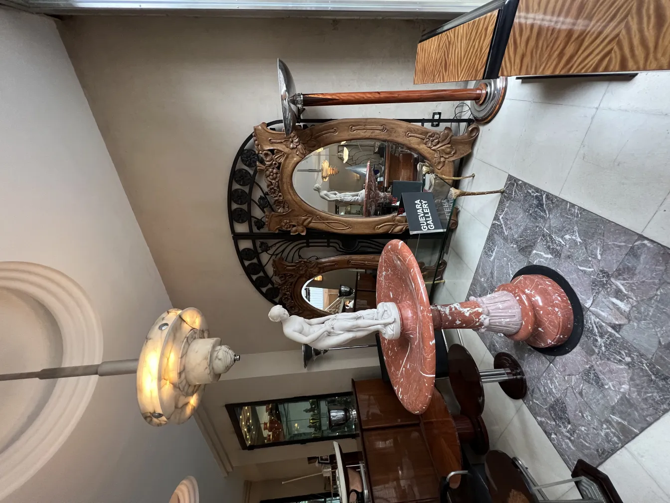 Escultura antigua de mármol en una decoración de interior elegante con espejos y luz suave.