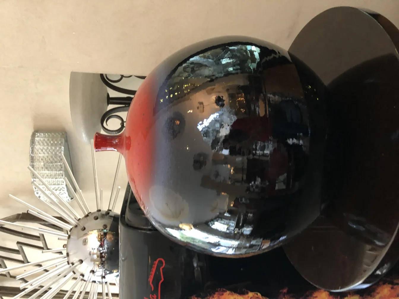 Vaso de cerâmica antiga com tons roxos e vermelhos, reflexos brilhantes.