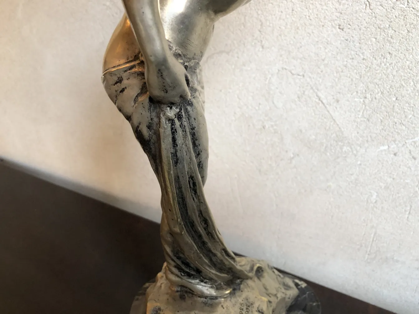 Scultura antica di donna in posa elegante, sfondo neutro
