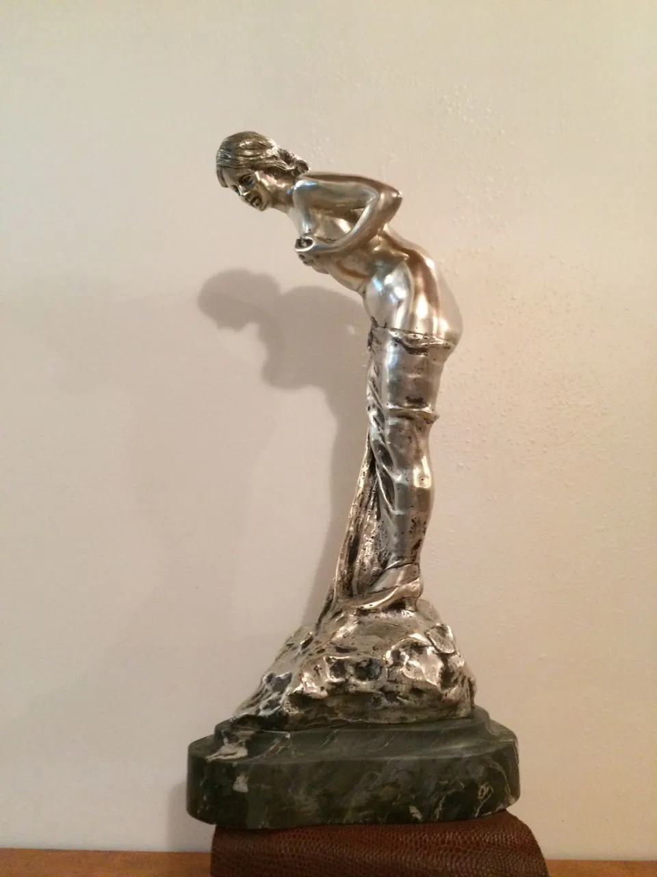 Antike Skulptur einer weiblichen Figur mit eleganten Details vor neutralem Hintergrund