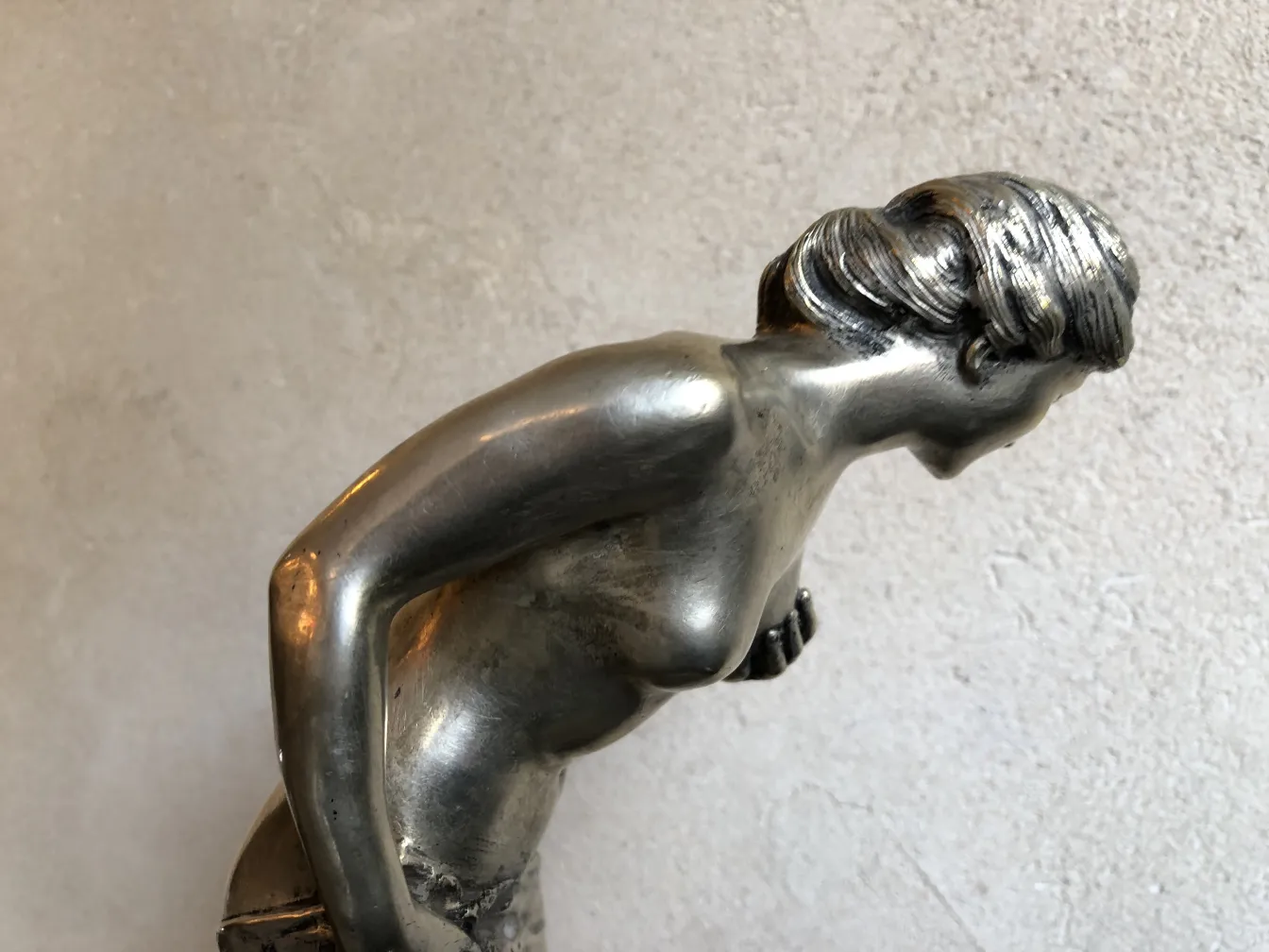 Scultura antica di figura femminile in posa inclinata, dettagli realistici.