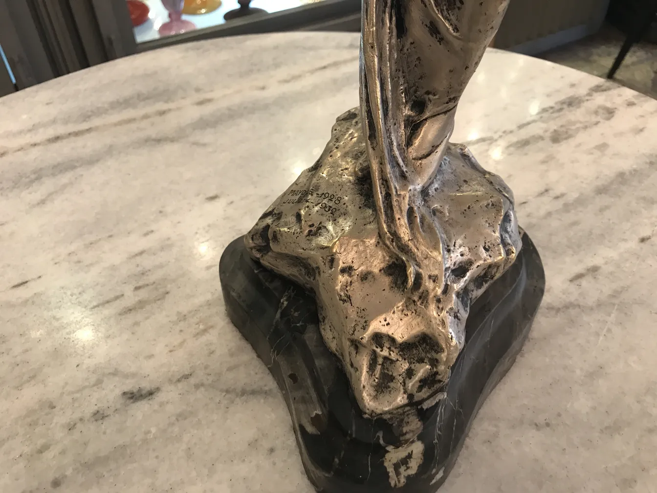 Escultura antigua con base decorativa, formas elegantes y detalles trabajados