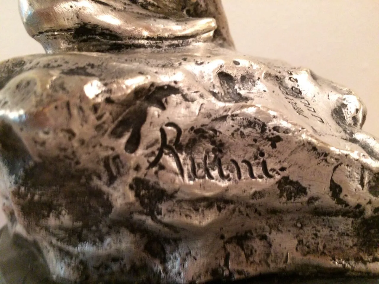 Detallada escultura antigua con firma visible en la base.