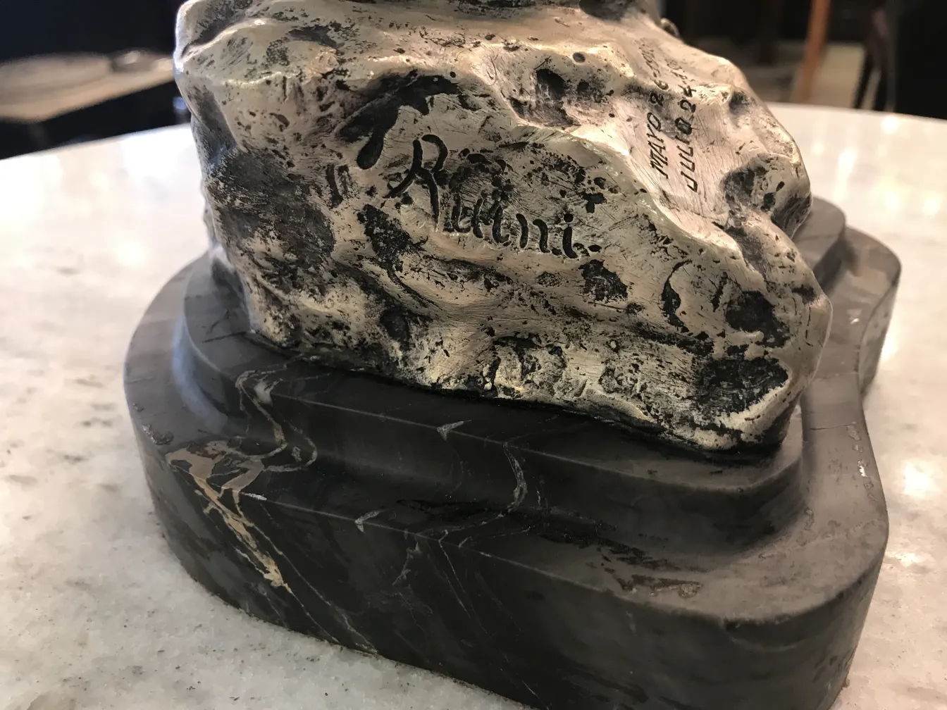 Scultura antica con base nera decorativa e dettagli superficiali