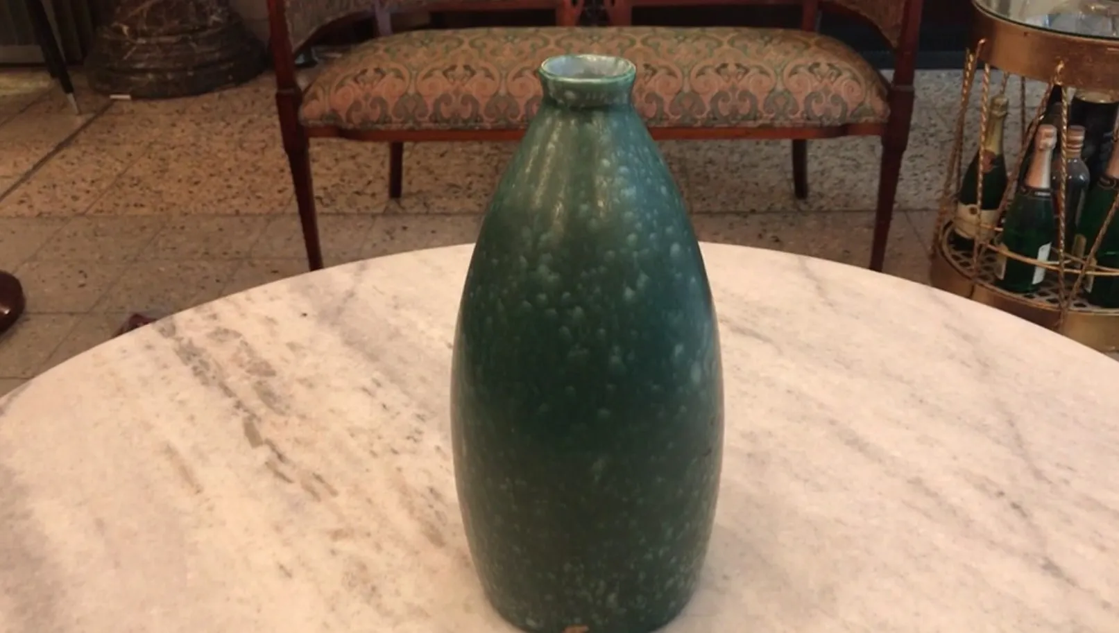 Antique green ceramic vase in pear shape on marble table.