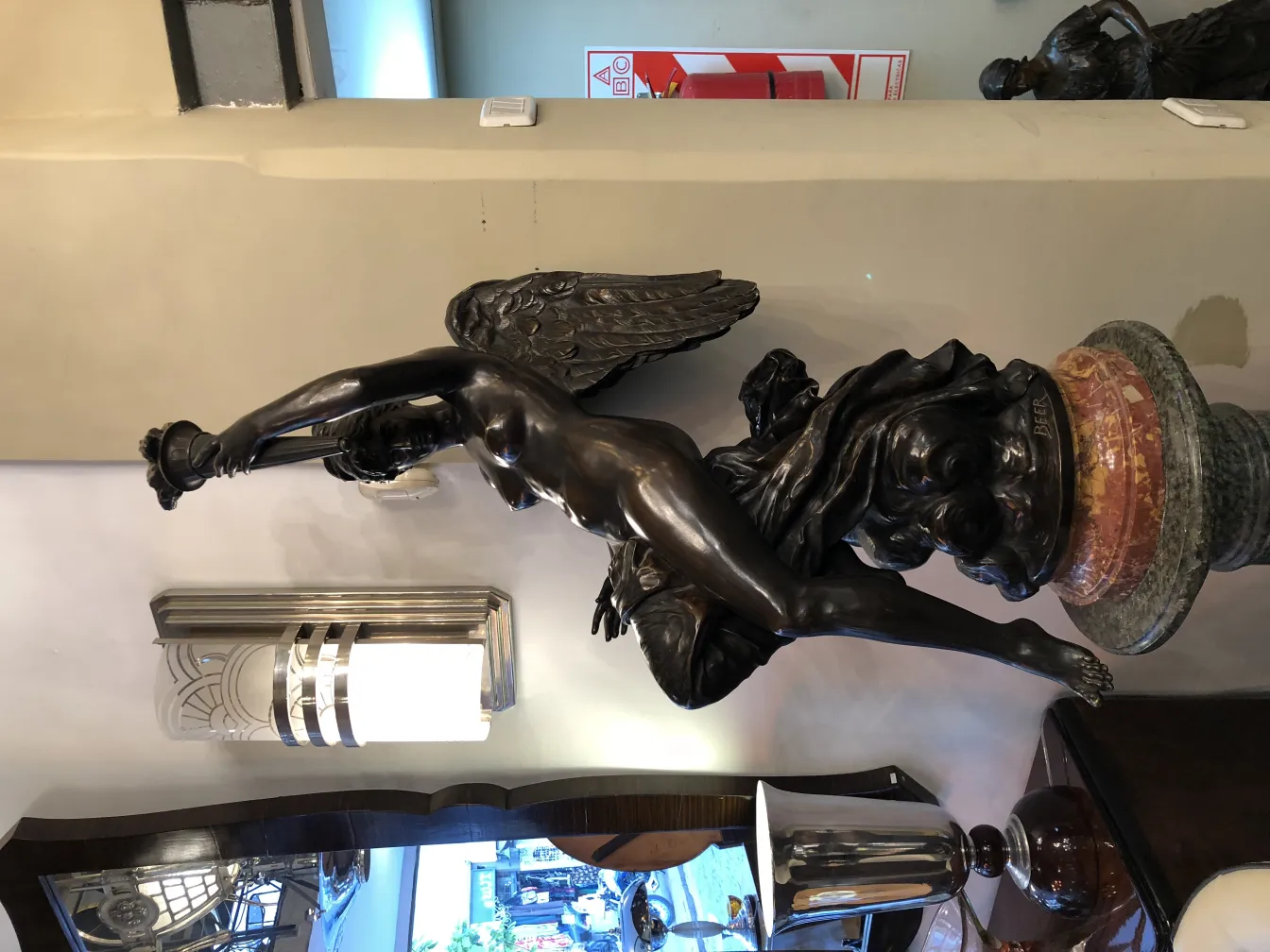 antique sculpture featuring winged figure and decorative base, beer