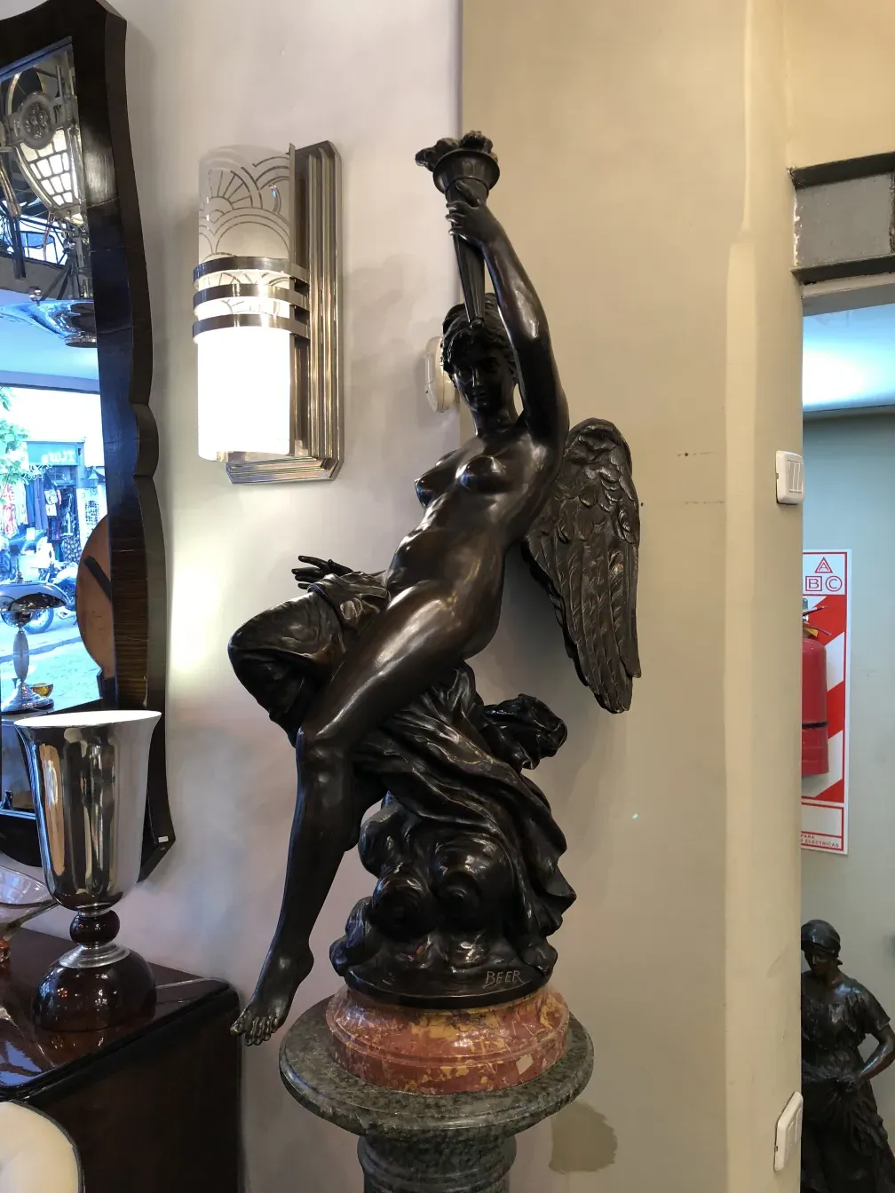 scultura antica con figura femminile e ali, in un ambiente elegante