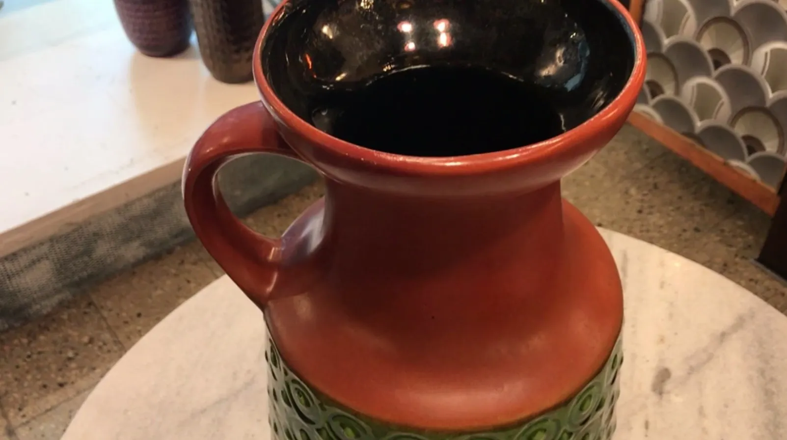 Antique ceramic jug with colorful decoration and unique texture.