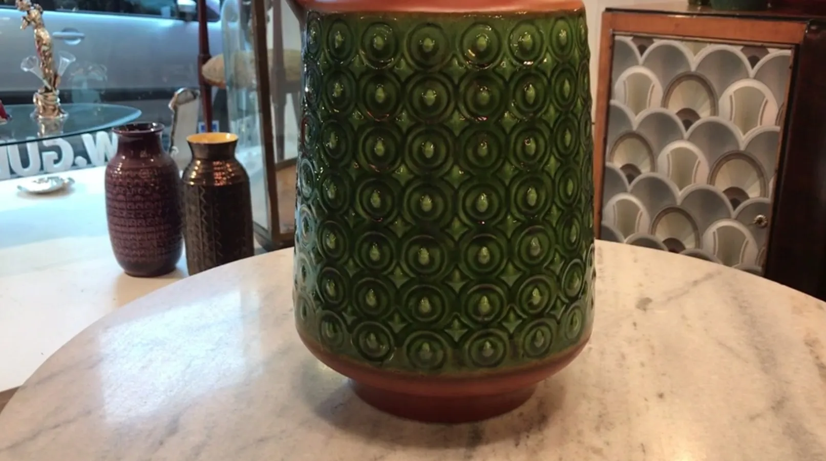 Vaso decorativo in ceramica antica verde con motivo circolare.