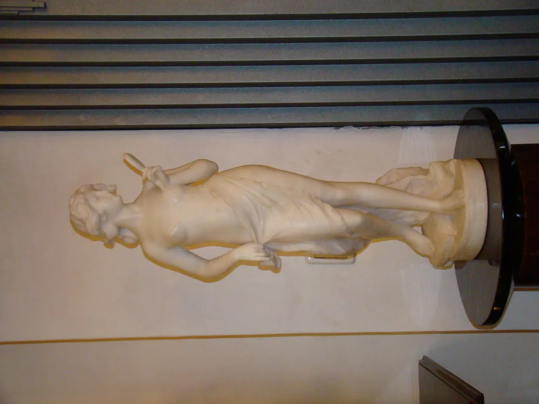 Sculpture ancienne d'une figure féminine dans un cadre neutre.