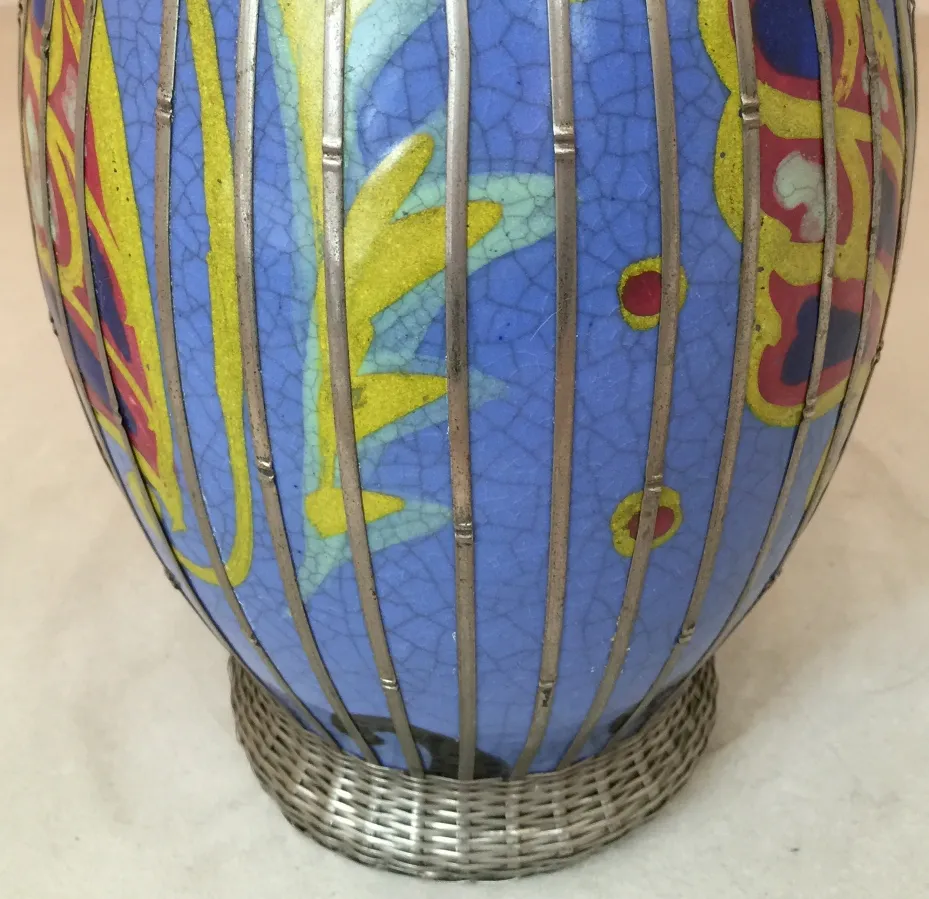 Antike Keramikvase, die mit lebendigen Farben und einzigartigen Designs verziert ist und eine Metallgitterbasis hat.