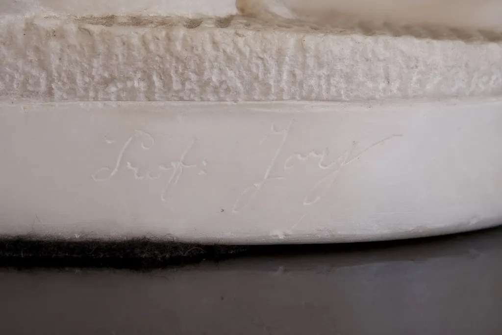 Antique sculpture featuring a visible signature at the base, artistic detail.