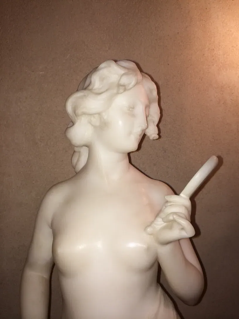 ancient sculpture of woman holding tool in hand