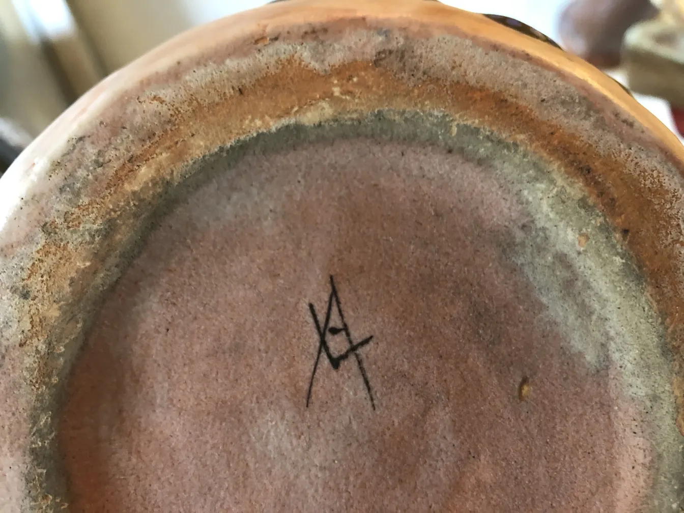 dettaglio della base di una ceramica antica con firma visibile.