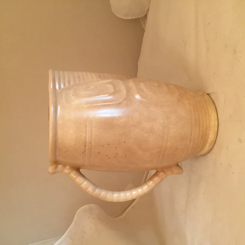 Anfora in ceramica antica con manici decorativi, colore chiaro.