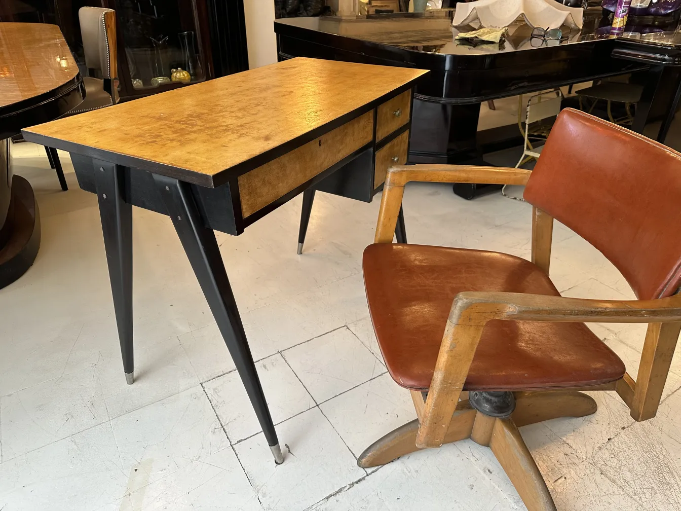 Bureau ancien en bois avec deux tiroirs et pieds élégants, dans une ambiance chaleureuse.