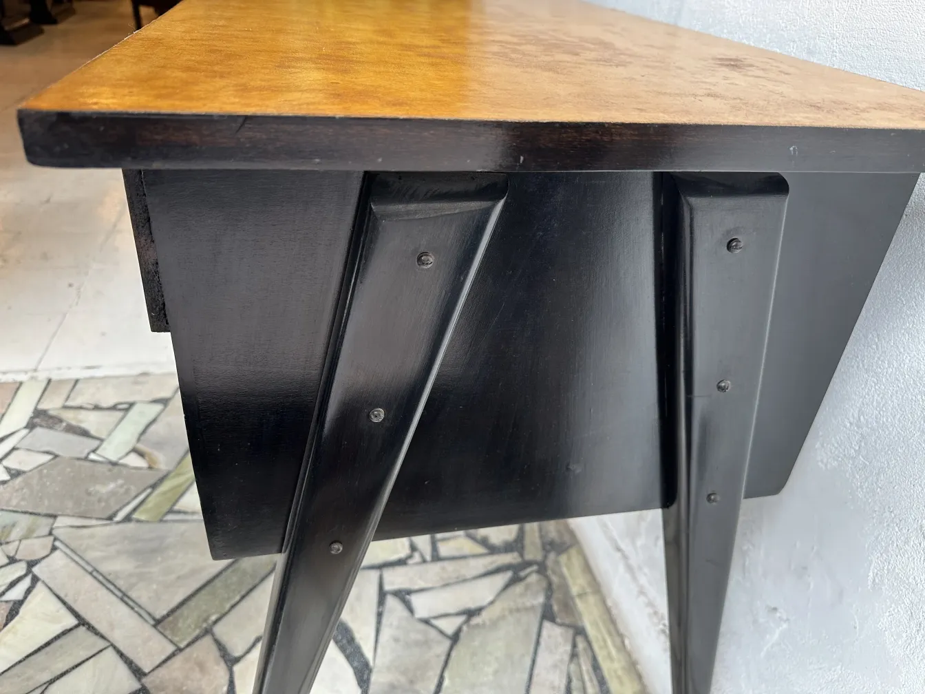 Bureau ancien avec surface en bois doré et pieds noirs.