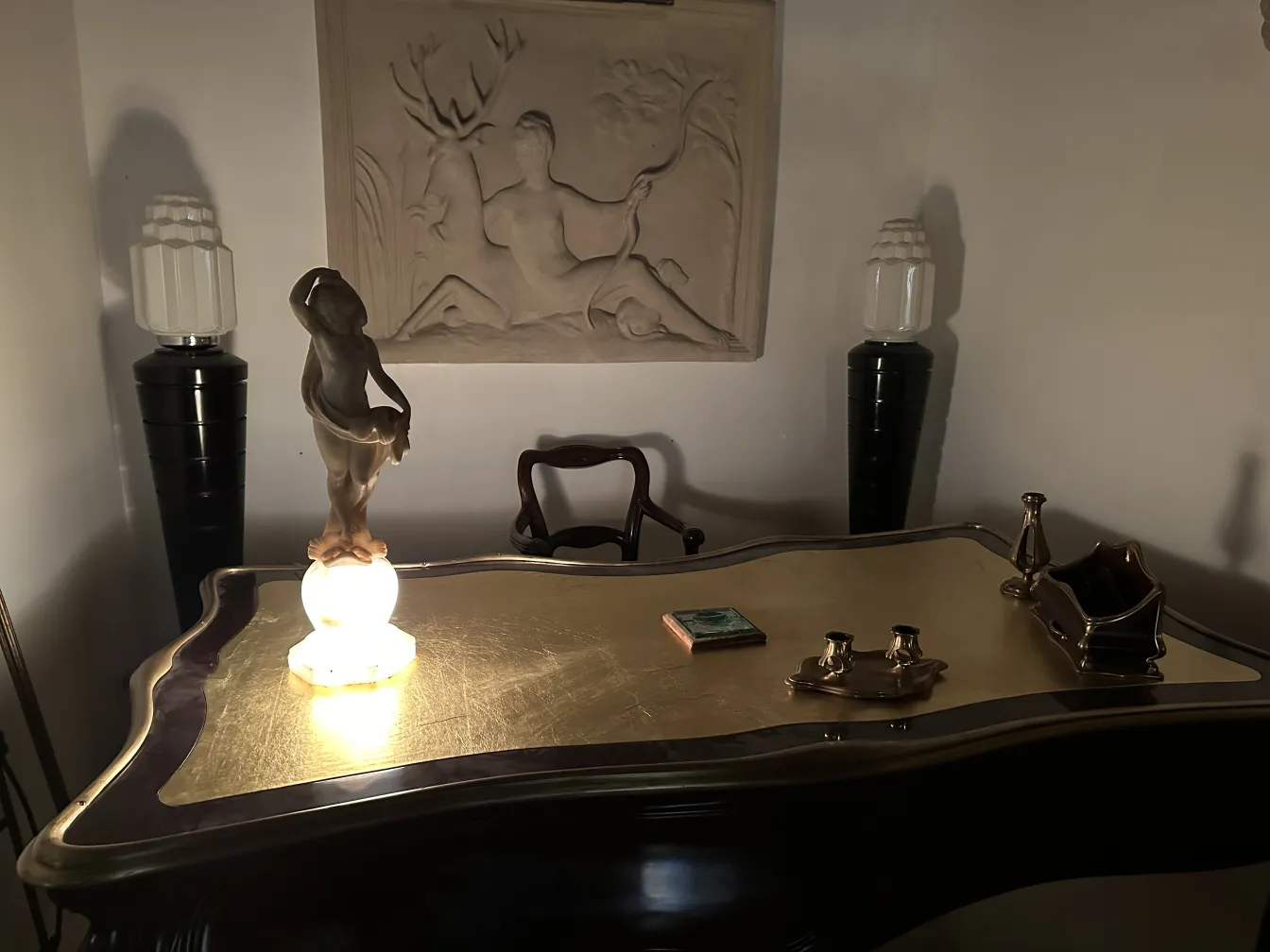 Escultura antiga de figura humana em cima de mesa dourada.