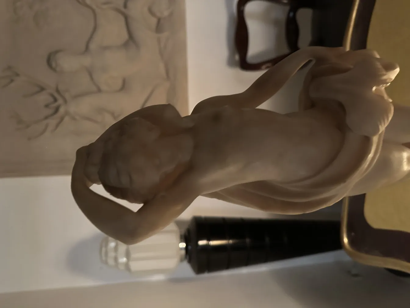 Klassische Skulptur mit menschlicher Figur im Detail, sanfter Hintergrund.