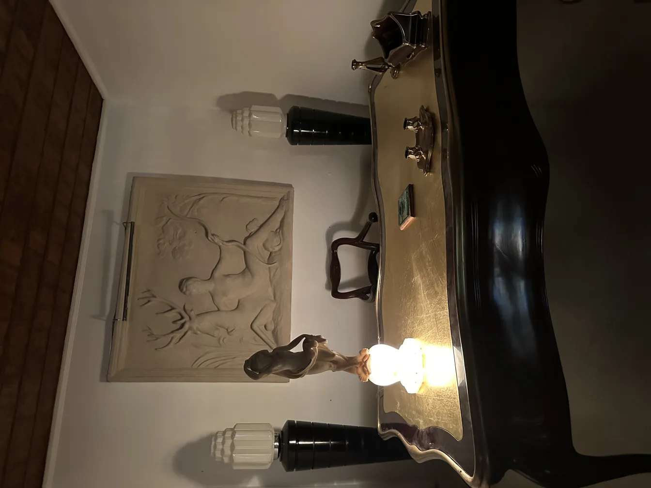 Ancient sculpture of human figure illuminated in elegant setting.