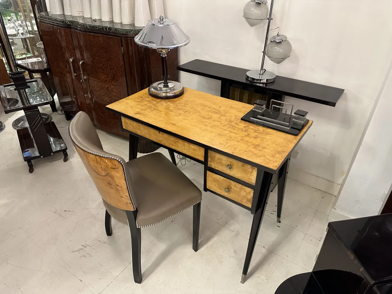 Antiker Schreibtisch mit heller Oberfläche und zwei Schubladen, zusätzlich mit einer Lampe.