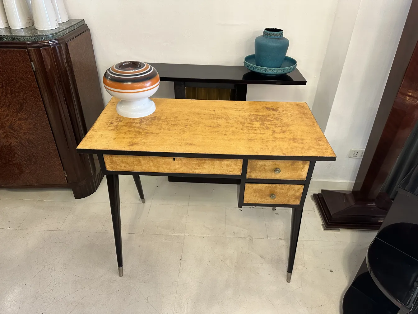 Scrivania antica con superficie gialla e due cassetti, decorata con un vaso.