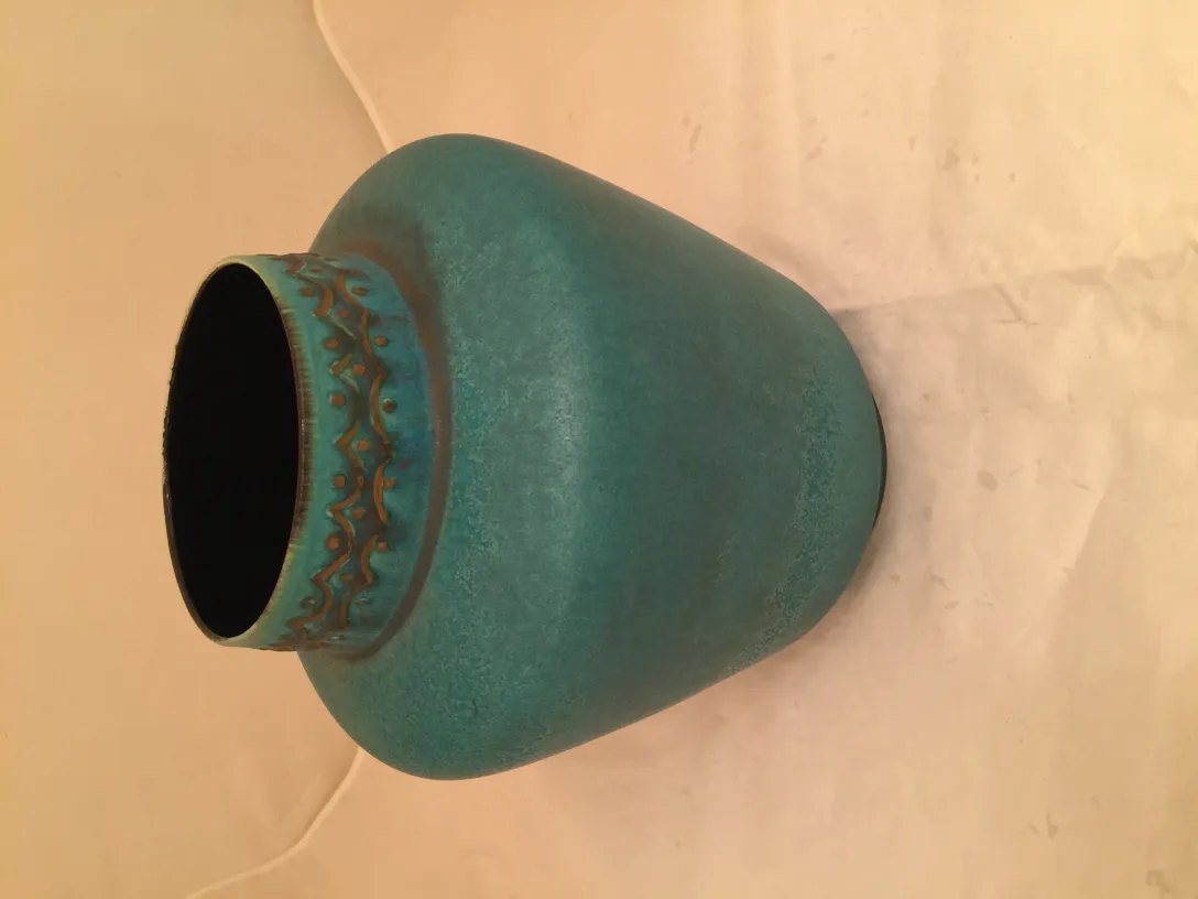 Vaso de cerámica antigua en color turquesa con un patrón decorativo.