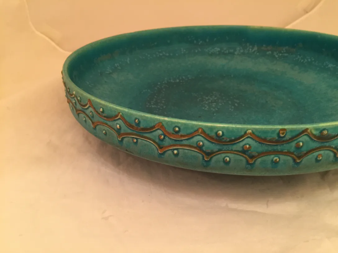 Piatto antico in ceramica turchese con dettagli. Sfondo morbido.