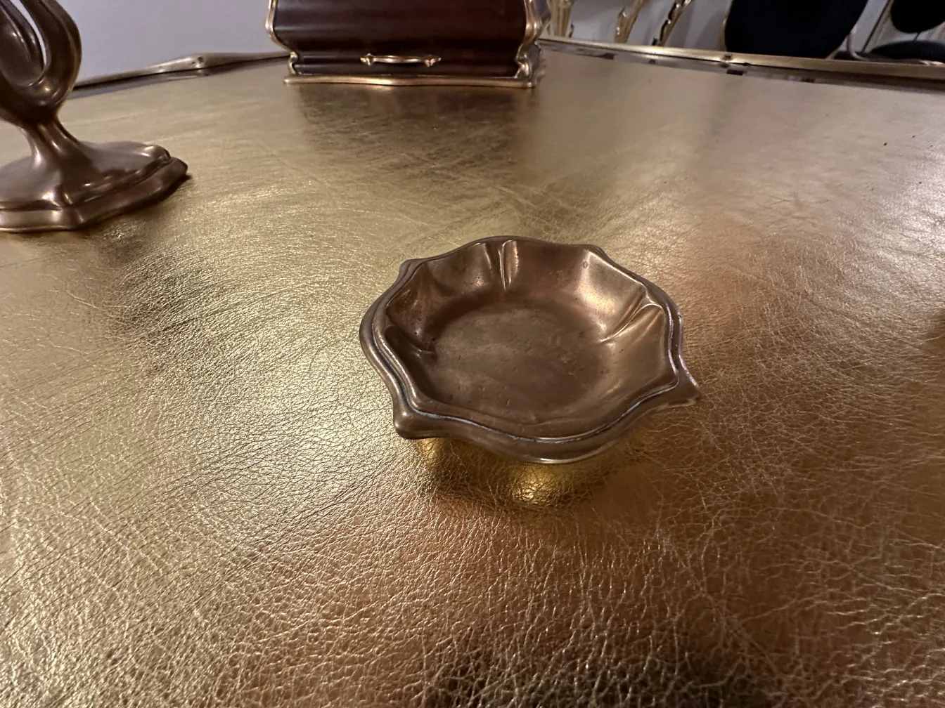 Plato antiguo en un escritorio dorado, con lámpara y otros accesorios.